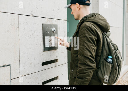 A male local resident or tourist clicks on the doorphone button or calls the intercom. Arrival and call from street to room Stock Photo