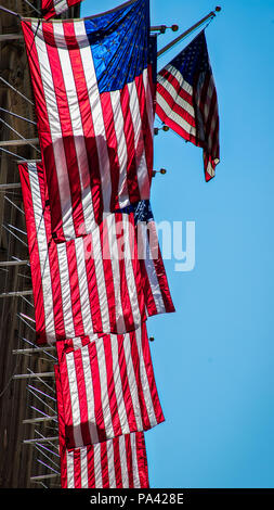 The sun shining on multiple American flags hanging from a building in New York. Stock Photo
