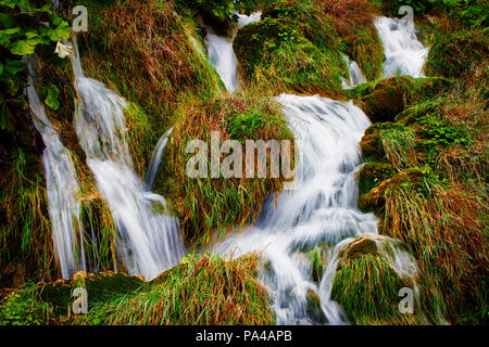 Water flows between mossy rocks Stock Photo