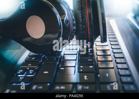 Black Wireless Gaming Or Deejay Headphone Lying On A Computer Keboard With Bright Light In The Background Stock Photo