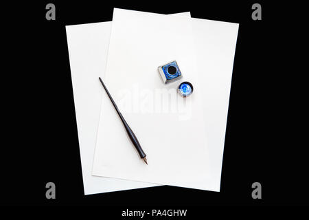 Two isolated white blank sheets of paper on black background, with pen and open bottle of blue ink, education concept, copy space for text Stock Photo