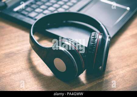 Black Wireless Overhead Headphones Lying On The Corner Of A Laptop Keyboard In An Office Stock Photo