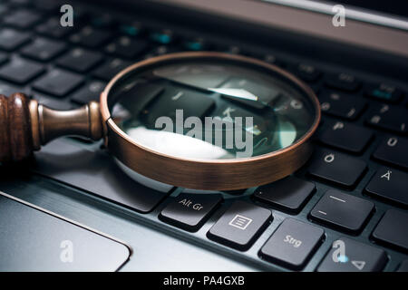 Vintage Magnifying Glass On A Black Notebook Keyboard - SEO Concept Stock Photo