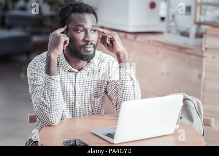 Nice serious man touching his temples Stock Photo