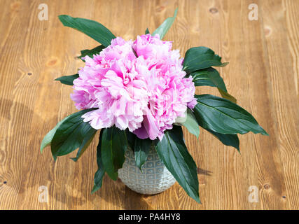 beautiful pink peonies in a vase on a wooden table, close-up in the spring Stock Photo