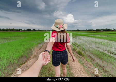 Young Asian women in red tops holding hand with partner at paddy field of Kedah, Malaysia. Kedah also known as the Rice Bowl State of Malaysia. Stock Photo
