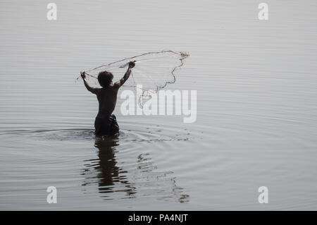 A fishermen in the Taung Tha Man Lake throws a fish net in the water, Myanmar Stock Photo