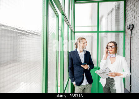 Business people talking phone standing in the beautiful green hall with glass partitions Stock Photo