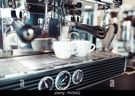 Espresso pouring from coffee machine into coffee cup. Stock Photo