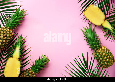 Half slice of fresh pineapple and whole fruit, palm leaves on yellow background. Top View. Copy Space. Bright pineapples pattern for minimal style. Po Stock Photo