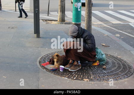 A poor man and his dog sit in the Paris street, waiting for help. Stock Photo
