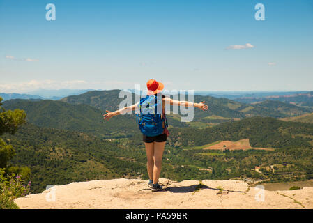 Hiker girl watching the beautiful view from the top of a cliff Stock Photo
