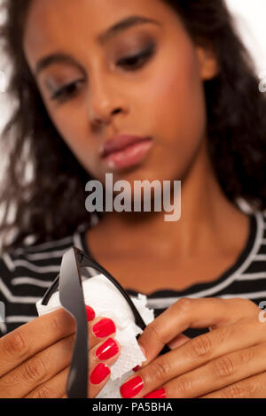 beautiful young dark skinned woman cleaning her eyeglasses Stock Photo