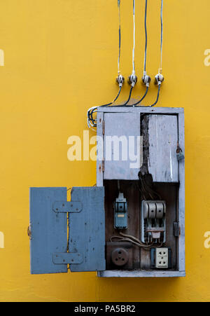 Wooden box, electric control equipment in the factory on yellow vintage concrete wall background. Manual cut out with old design. Safety in home and f Stock Photo