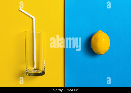 Lemons on split colored background with glass and straw. Stock Photo