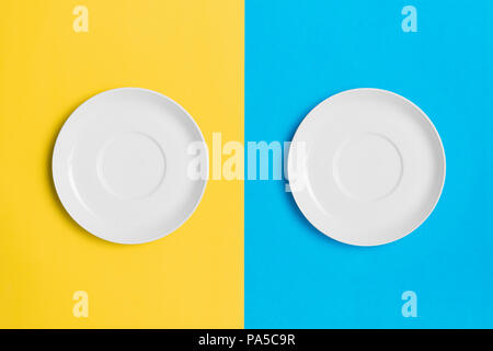 Empty plates on a contrasting yellow and blue background. Stock Photo