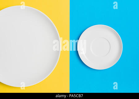 Empty plates on a contrasting yellow and blue background. Stock Photo