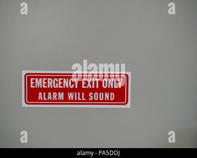 Emergency exit only, alarm will sound sign posted on a white door Stock Photo