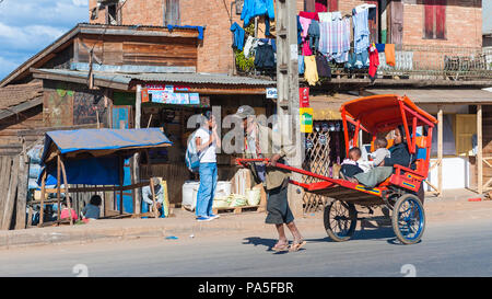 ANTANANARIVO, MADAGASCAR - JUNE 29, 2011: Unidentified Madagascar man carries  a transporting carriage with mother and children. People in Madagascar  Stock Photo