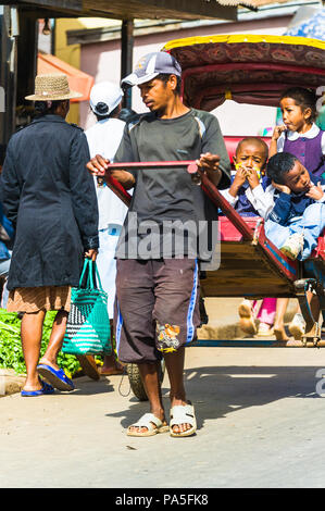 ANTANANARIVO, MADAGASCAR - JUNE 30, 2011: Unidentified Madagascar man carries a carriage with children. People in Madagascar suffer of poverty due to  Stock Photo