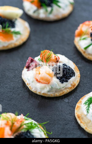 Selection of cocktail blinis with salmon, cured bresaola, crayfish, caviar, quail eggs and sour cream - gourmet party food Stock Photo