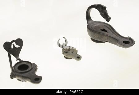 From left to right: lamp with heart shaped plate, from Cologne; pendant lamp with lid, from Luxembourg Street, Cologne and lamp with handle in the shape of horse head, of unknown origin. Roman-Germanic Museum. Cologne. Germany. Stock Photo
