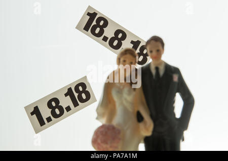 Munich, Germany. 10th July, 2018. A pair of bride and groom figurines stand on a table in front of the dates '01.08.2018 and 18.08.2018'. The registry office records that requests for such supposedly lucky wedding dates have been unusually few this year. Credit: Lino Mirgeler/dpa/Alamy Live News Stock Photo