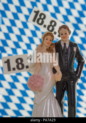 Munich, Germany. 10th July, 2018. A pair of bride and groom figurines stand on a table in front of the dates '01.08.2018 and 18.08.2018'. The registry office records that requests for such supposedly lucky wedding dates have been unusually few this year. Credit: Lino Mirgeler/dpa/Alamy Live News Stock Photo