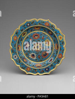 Dish with scalloped rim. Culture: China. Dimensions: H. 1 in. (2.5 cm); Diam. 6 in. (15.2 cm). Date: early 15th century.  Lively scrolling lotuses and acanthus leaves are set against a turquoise blue background on the interior (and parts of the exterior) of this dish. In fifteenth-century examples, this background color is often combined with shades of red, yellow, cobalt blue, white, and dark green, which were not mixed but placed individually within each cloison. Although cloisonné was known in China in the fourteenth century, fifteenth-century pieces, such as this dish, are the earliest pre Stock Photo