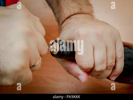 Opening a bottle of wine close-up. Men's hands get a corkscrew plug. Stock Photo
