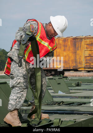 A cargo specialist with the 1174th Deployment and Distribution Battalion at Fort Totten, New York, inspects straps securing cargo during Transmariner 2016 at Military Ocean Terminal Sunny Point, North Carolina. Transmariner is an Army Reserve exercise where soldiers receive, inspect, repackage, and prepare munitions for loading onto ships. The training emphasizes logistics, cargo security, safety procedures, and operational coordination for maritime deployment readiness. Stock Photo