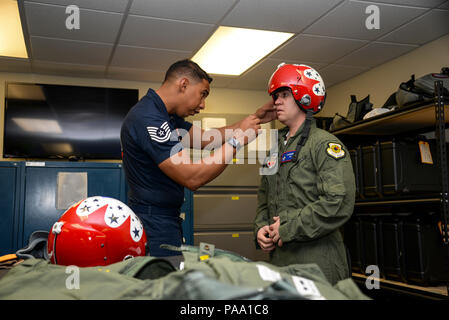U.S. Air Force Tech. Sgt. Paul Rosales, aircrew flight equipment specialist with the U.S. Air Force Air Demonstration Squadron, inspects the fit of a helmet on Brendan Lyons, Tucson community hometown hero, at Davis-Monthan Air Force Base, Ariz., March 11, 2016. Lyons was nominated as a hometown hero to fly with the Thunderbirds because of his commitment to safety and his passion to make Tucson a safer community for cyclists and motorists. (U.S. Air Force photo by Senior Airman Chris Massey/Released) Stock Photo