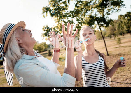 Joyful elderly woman catching bubbles Stock Photo