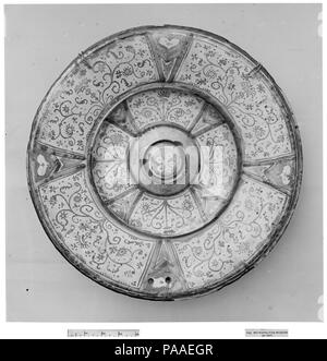 Dish. Culture: Spanish. Dimensions: Diameter: 16 in. (40.6 cm). Date: 18th century.  Tin-glazed earthenware, of which lusterware is one type, was developed in the Middle East in the ninth and tenth centuries to imitate the porcelains produced in China. The opaque white glaze concealed the clay body, which could range from pale buff to brick red, allowing for brilliant effects created by painting the white surface with metal oxides that fired to a range of colors. This technique, as well as the use of metallic luster--an iridescent, coppery painted glaze--spread throughout the Muslim world, arr Stock Photo