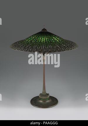 'Lotus, Pagoda' lamp. Culture: American. Dimensions: 31 1/2 in. (80 cm)  Body diameter: 26 3/8 in. (67 cm). Maker: Tiffany Studios (1902-32). Date: ca. 1900-15.  Although Tiffany Studios is famous for leaded-glass floral motif shades, it also created arresting geometric designs, such as this 'Lotus Pagoda' lamp. This example--the largest and rarest of this design--was owned by an apprentice who worked in Frank Lloyd Wright's studio. A similar model was among the furnishings displayed at Fallingwater, the landmark house Wright designed for Edgar Kaufmann in 1936. The design of the shade is base Stock Photo