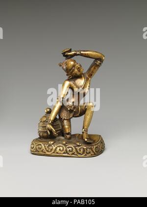 Ascetic Master, probably a Mahasiddha. Culture: Tibet. Dimensions: H. 4 3/4 in. (12.1 cm); W. 3 in. (7.6 cm); D. 2 1/4 in. (5.7 cm). Date: 17th century.  A dramatically poised Indian yogi kneels on a flayed buffalo skin and holds aloft a skull cup. He is likely the mahasiddha Kapalapa ('Skull-cup Bearer'), one of the Indian eccentric yogis and practitioners of Tantrism so revered in the Tibetan Vajrayana tradition. This icon likely portrays a Dzogchen master of the Nyingma order who practiced as an ascetic yogi. Museum: Metropolitan Museum of Art, New York, USA. Stock Photo