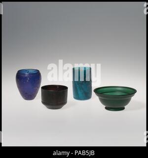 Glass cup. Culture: Roman. Dimensions: H.: 2 5/16 in. (5.9 cm)  Diam.: 2 5/16 in. (5.9 cm). Date: early 1st century A.D..  Translucent deep purple.  Vertical rim with slightly beveled outward lip; vertical side to cylindrical body, then slanting in diagonally to concave bottom.  On exterior, at bottom of vertical side a band of two horizontal raised lines, the upper one being thicker and more pronounced, another band of two raised lines around outer edge of diagonal underside, and a third band of two raised lines around edge of bottom.  Intact; a few bubbles; dulling, pitting, and patches of c Stock Photo