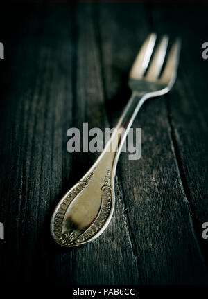 old vintage fork on rustic wooden table in dark atmosphere with green ribbon Stock Photo