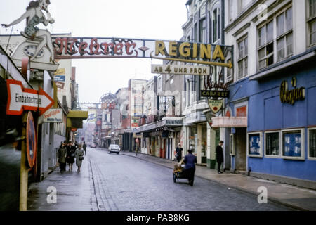 1960s view of Regina Cabaret and Night Club in daylight, Grosse Freiheitstrasse, Reeperbahn, Hamburg, Germany, with man pushing cart down cobbled road Stock Photo