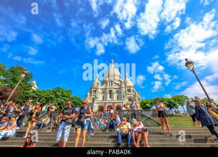 Paris, France - July 3, 2017: many people on the stairs of Basilica of Sacre Coeur de Montmartre in Paris in a sunny day with blue sky. Sacred Heart Church is a popular tourist landmark. Bottom view. Stock Photo