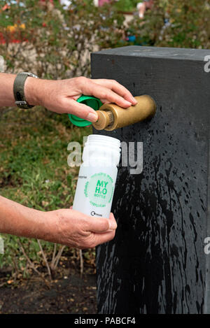 Man filling reusable plastic water bottle from modern water fountain, Kings Cross, London Borough of Camden, England Britain UK Stock Photo