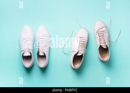 Old dirty sneakers vs new white sneakers on blue background. Trendy footwear. Top view. Concept of experience, discipline and chaos, accuracy  mess,  Stock Photo