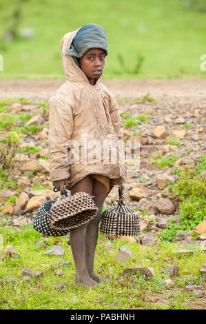 AKSUM, ETHIOPIA - SEPTEMBER 22, 2011: Unidentified Ethiopian boy sells the traditional hat with the green nature background. People in Ethiopia suffer Stock Photo