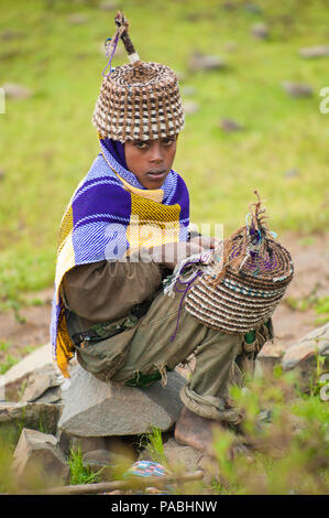 AKSUM, ETHIOPIA - SEPTEMBER 22, 2011: Unidentified Ethiopian boy sells the traditional hat with the green nature background. People in Ethiopia suffer Stock Photo