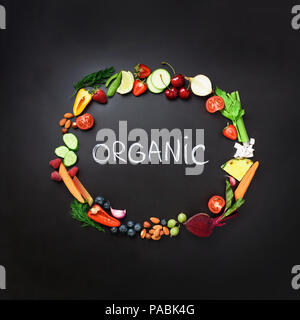 Healthy food background. Circle of fresh vegetables, fruits, nuts, berries with handwritten phrase Organic on black chalkboard. Square crop. Top view. Stock Photo