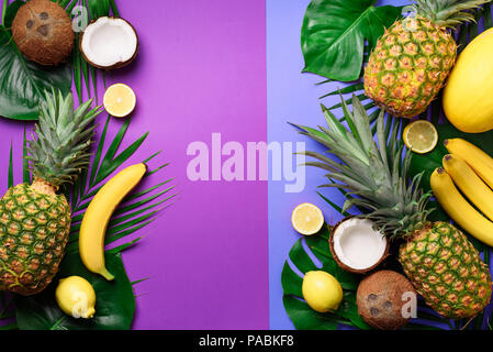 Exotic pineapples, coconuts, banana, melon, lemon, tropical palm and green monstera leaves on purple, violet background with copyspace. Creative layou Stock Photo