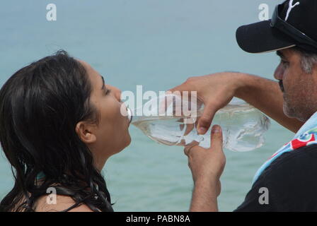 The father gives his daughter some water from a plastic bottle. Stock Photo