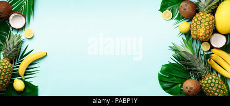 Banner of exotic pineapples, ripe coconuts, tropical palm and monstera leaves on blue background with copyspace for your text. Creative layout. Summer Stock Photo