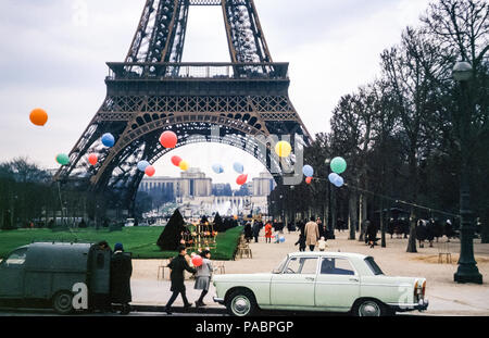 View of the base of the Eiffel Tower with Trocadero fountains viewed from Parc du Champs de Mars, Paris, France, with old fashioned cars and balloons in the 1960s Stock Photo
