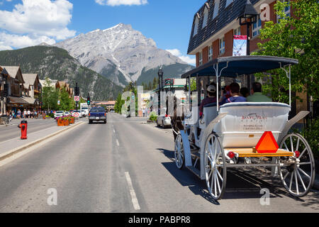 Banff, Alberta, Canada - June 20, 2018: Tourists are taking a tour on a hourse around the city. Stock Photo